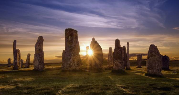 Menhires al atardecer proyectando largas sombras.