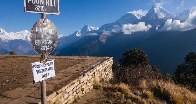Panneau de Poon Hill avec des montagnes enneigées en arrière-plan.