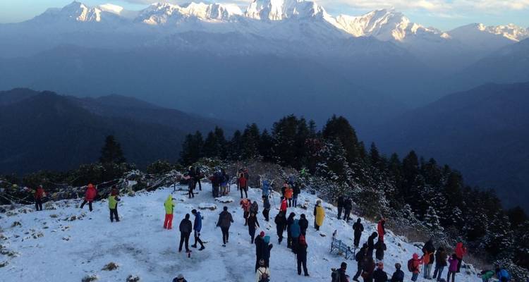 Foule de personnes sur un point de vue de montagne enneigée.