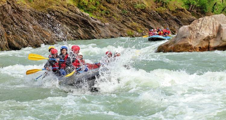 Groupe de personnes faisant du rafting en eaux vives avec des éclaboussures d'eau.