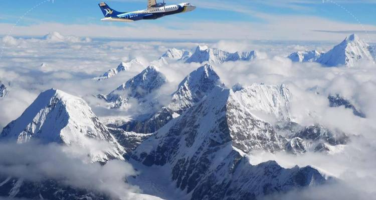Airplane flying over snow-capped mountains.