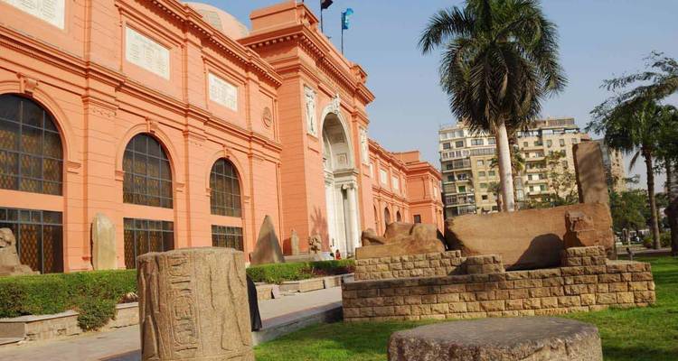 Buitenkant van het Egyptisch Museum in Caïro met artefacten in de tuin.