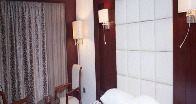 Een hotelkamer met een bed en stoelen bij het raam.