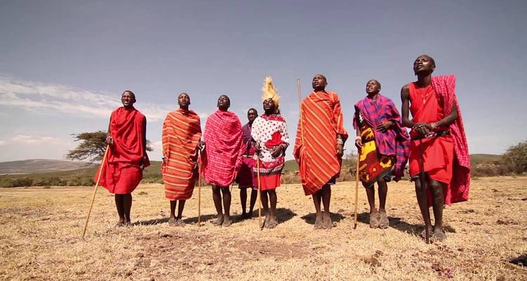 Group of people in traditional Maasai attire standing on a plain.