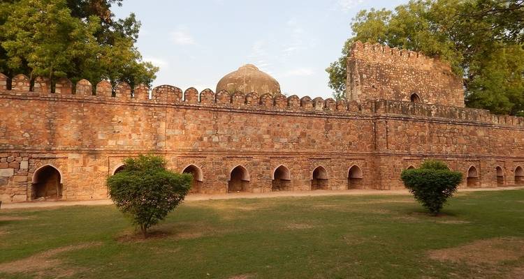 Alte Festungsmauer mit Bäumen und einem Garten davor.