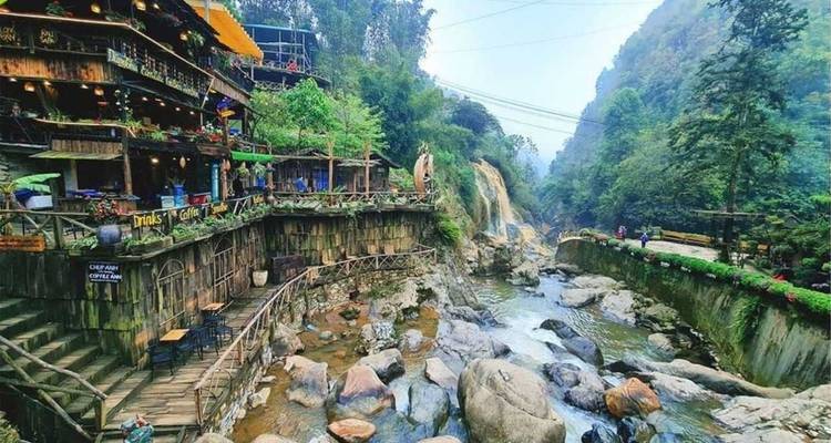 Cascade et un village pittoresque traversé par une rivière.