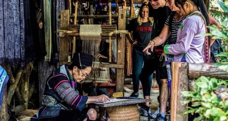 Artisan local faisant une démonstration de tissage artisanal avec des touristes qui observent.