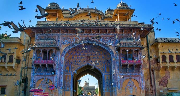 Colorful archway with pigeons flying in front.