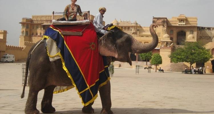Elephant ride experience near historic fort with two people.