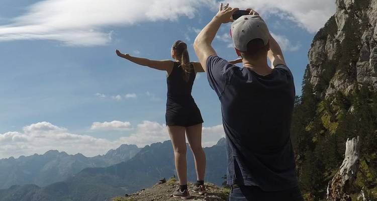 Zwei Personen posieren auf einem Berggrat mit weitläufigem Blick ins Tal.
