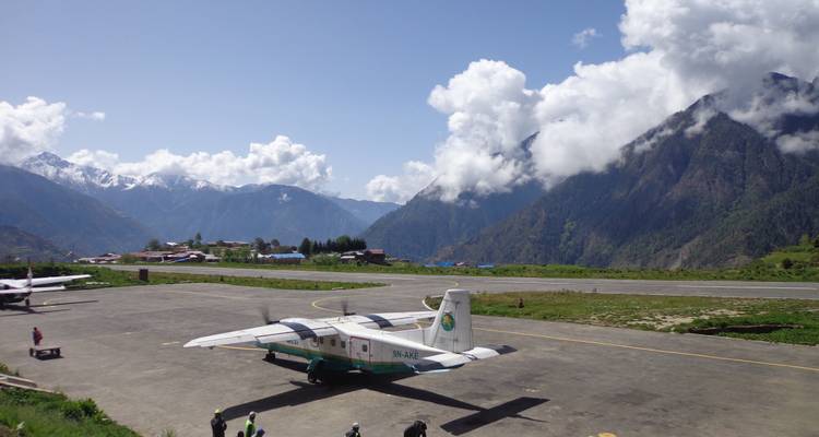 Small aircraft parked on a mountain airstrip with scenic hills around.