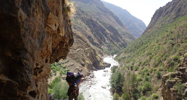A rugged mountainous river valley with a hiking path.