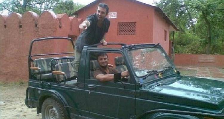 Deux hommes dans une jeep à l'extérieur, l'un pointant vers l'extérieur.