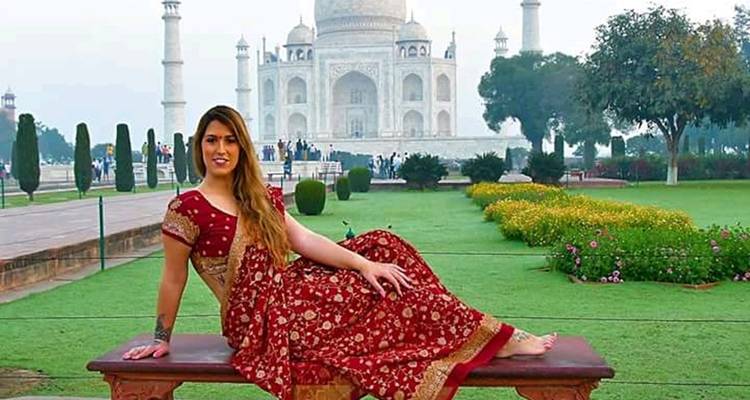 Frau in traditioneller Kleidung, die vor dem Taj Mahal liegt.