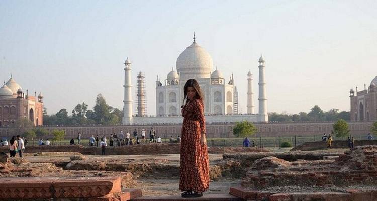Frau posiert vor dem Taj Mahal mit Touristen im Hintergrund.