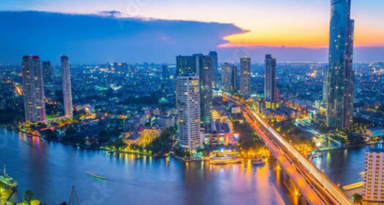 Cityscape of Bangkok with river and skyscrapers at sunset.