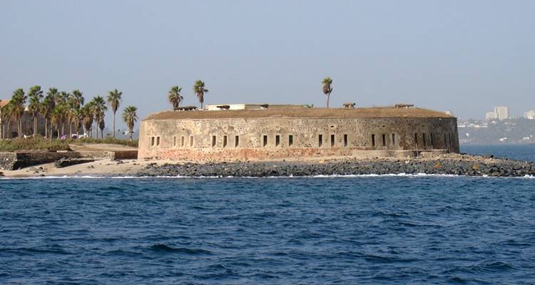 Un bâtiment ressemblant à un fort sur une côte avec des palmiers.