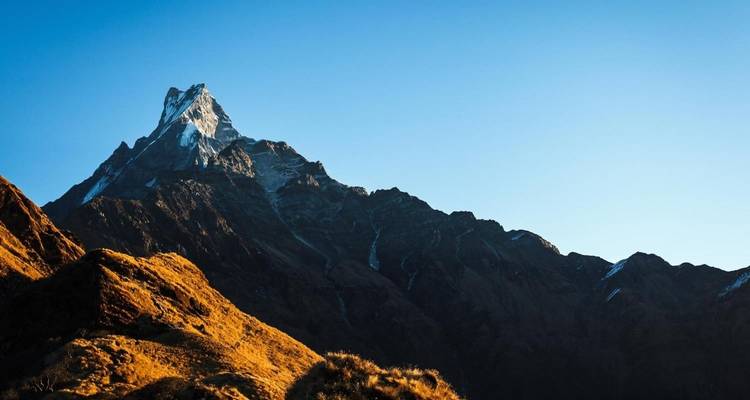 Een prominente met sneeuw bedekte bergtop onder een heldere hemel.
