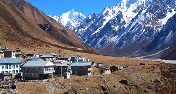 A village surrounded by mountains with a snowy background.