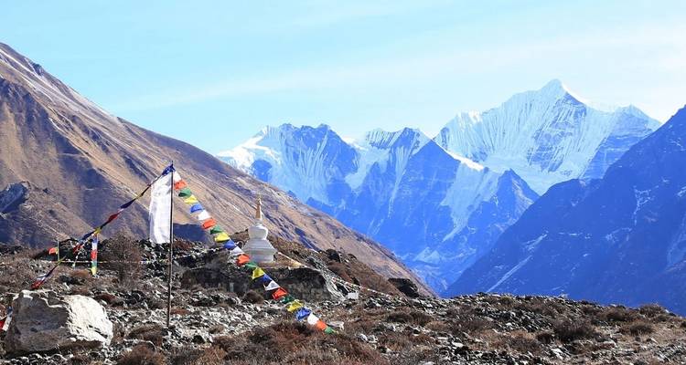 Mountains with prayer flags and a stupa in the foreground.
