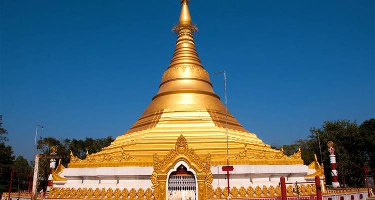 Eine goldene Stupa unter einem klaren blauen Himmel.