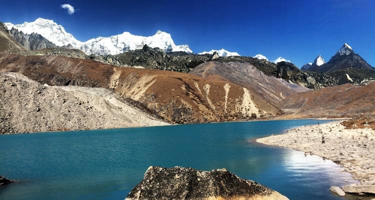A lake in the mountains, with snow-capped peaks in the background.