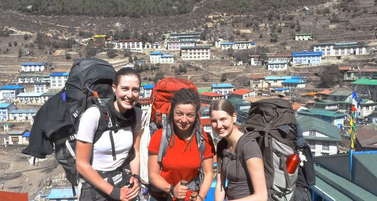 Three hikers posing in a mountainous village with colorful houses.