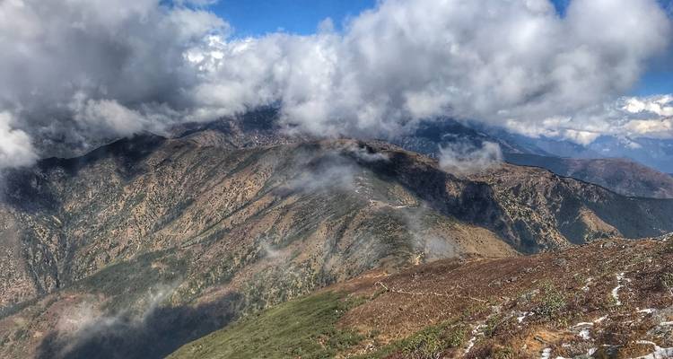 Mistig berglandschap met verspreide wolken.