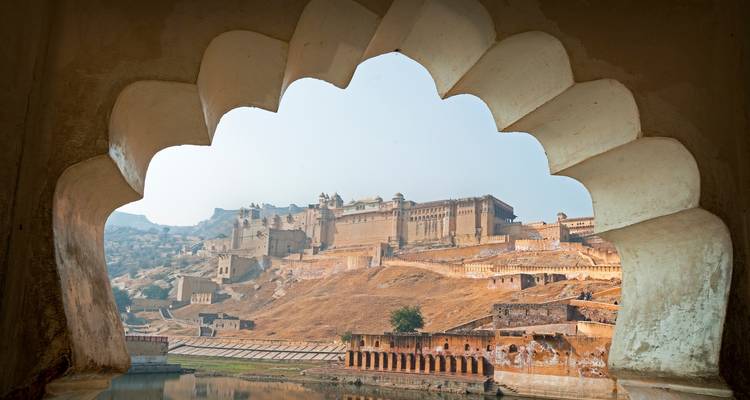 Fuerte Amber visto a través de una ventana de arco festoneado que refleja la arquitectura rajput y las colinas áridas.