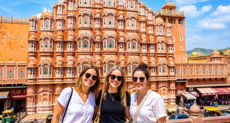 Drie reizigers glimlachend voor de ingewikkeld gelaagde gevel van Jaipur's Hawa Mahal.