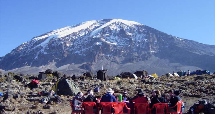 Groupe de personnes dans un camping avec le mont Kilimandjaro en arrière-plan.