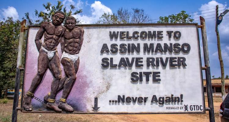 Panneau du site de la rivière des esclaves d'Assin Manso avec sculptures.