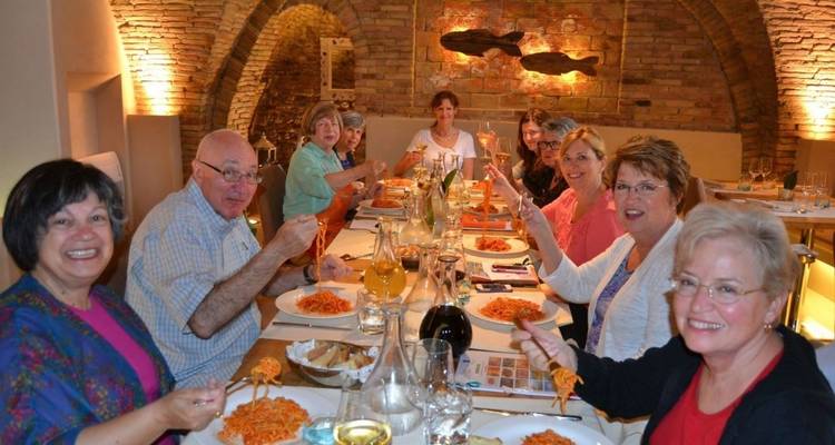 Un grupo de personas cenando con platos de pasta en el interior.