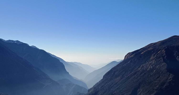 A clear view of a misty mountain range with valleys under a blue sky.