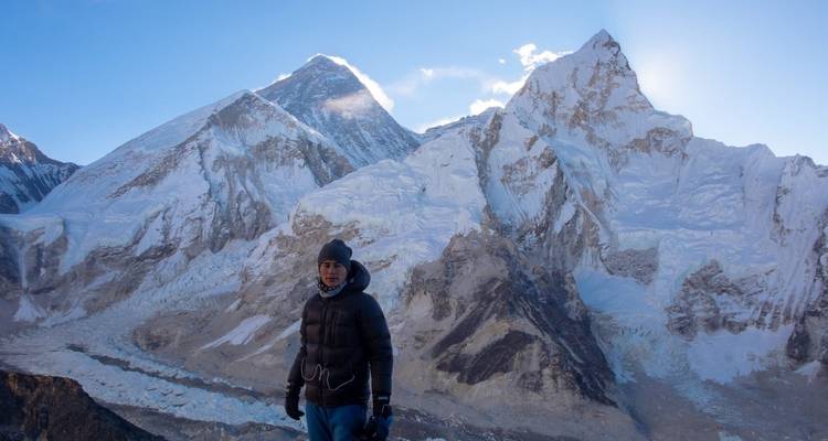 Personne posant avec des montagnes enneigées en arrière-plan.