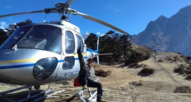 Personne assise sur un hélicoptère dans une zone montagneuse.