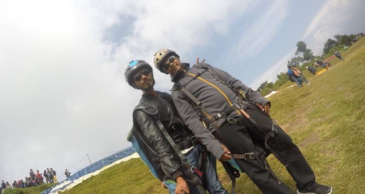 Zwei Personen in Outdoor-Ausrüstung stehen auf Gras bei klarem Himmel.