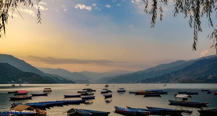 Lake with boats and mountains at sunset.
