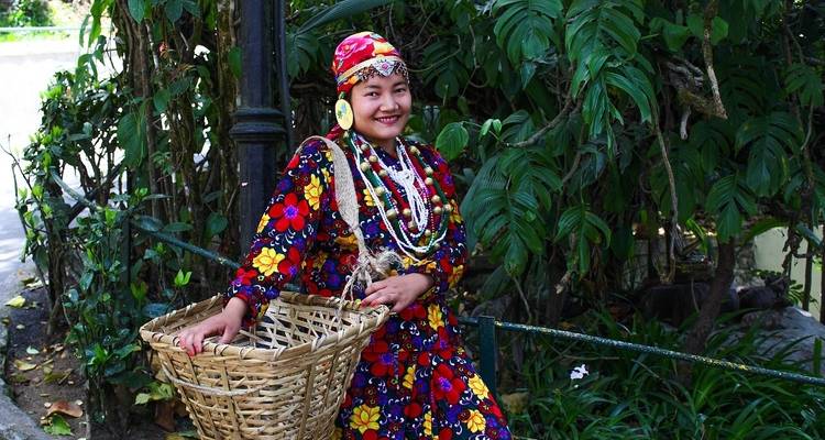 Person in traditional attire with a basket in a garden.