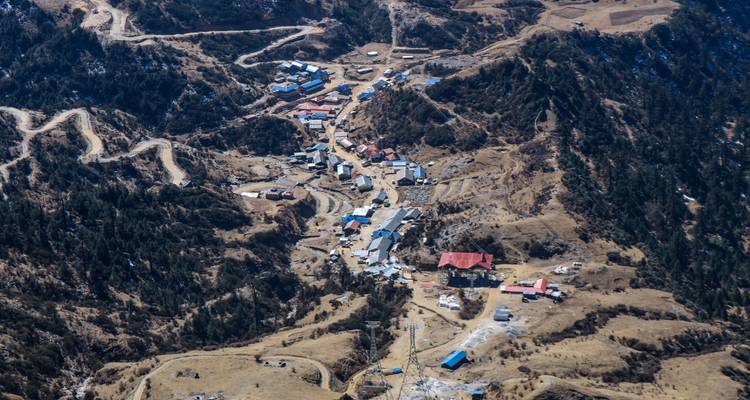 Luftaufnahme eines kleinen Dorfes inmitten von Hügeln.