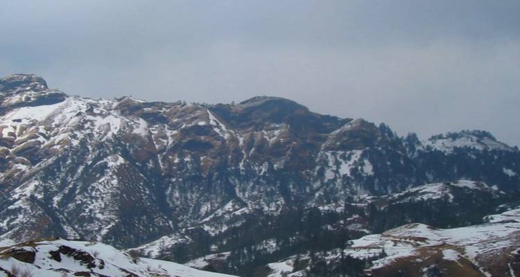 Schneebedeckte Berggipfel unter einem bewölkten Himmel.