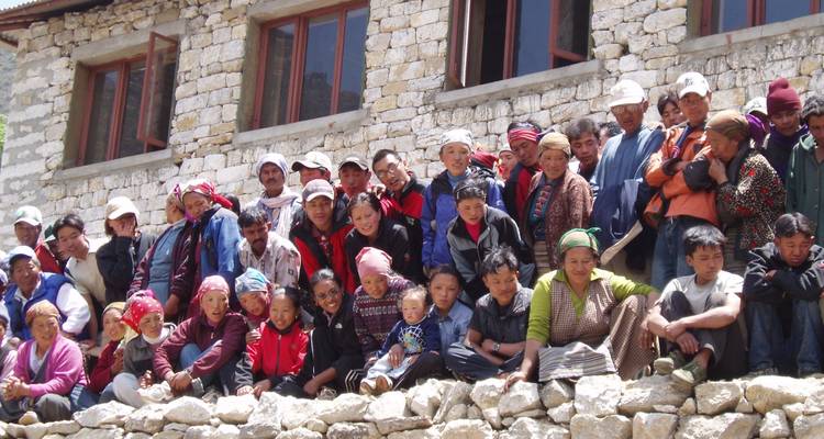 Portrait de groupe nombreux devant un bâtiment en pierre.