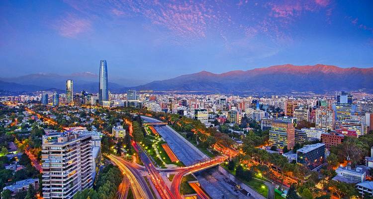 Vista aérea de un paisaje urbano moderno con montañas al fondo al atardecer.