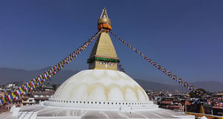 Boudhanath-Stupa mit bunten Gebetsfahnen, die von seiner goldenen Spitze herabhängen.