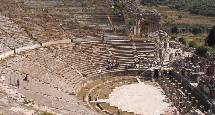 Gran anfiteatro antiguo with varios visitantes explorando.

Wait, let me correct that - I mixed languages. Here's the proper Spanish translation:

Gran anfiteatro antiguo con algunos visitantes explorando.