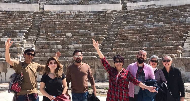 Turistas posando frente a un gran anfiteatro de piedra.