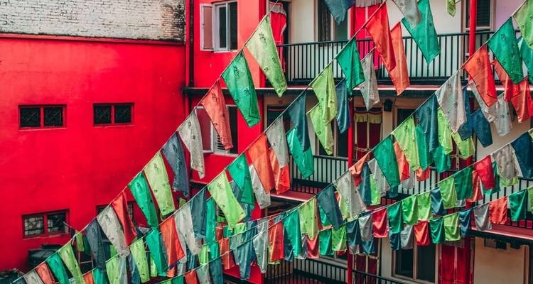 Colorful prayer flags in front of a red building.