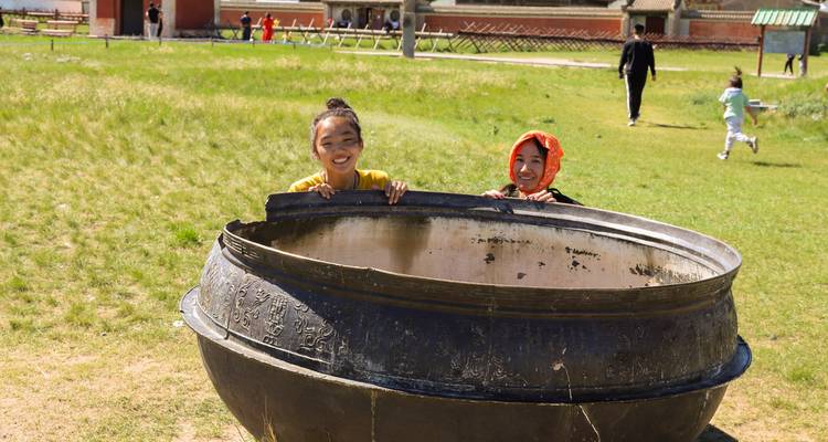 Children peeking out from a large pot in a park
