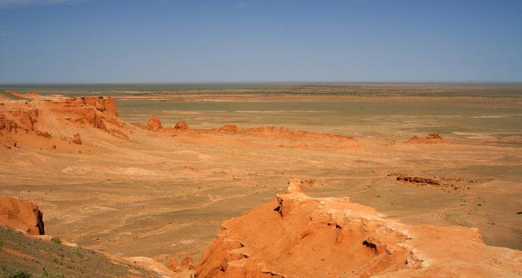 Vast desert landscape with red rocky formations.