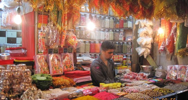 Winkelier in een levendige marktkraam die kruiden en decoraties verkoopt